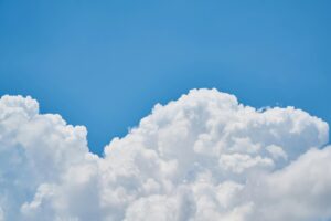 Bright blue sky with large, fluffy white clouds rising high into the atmosphere, creating a vibrant and serene scene.